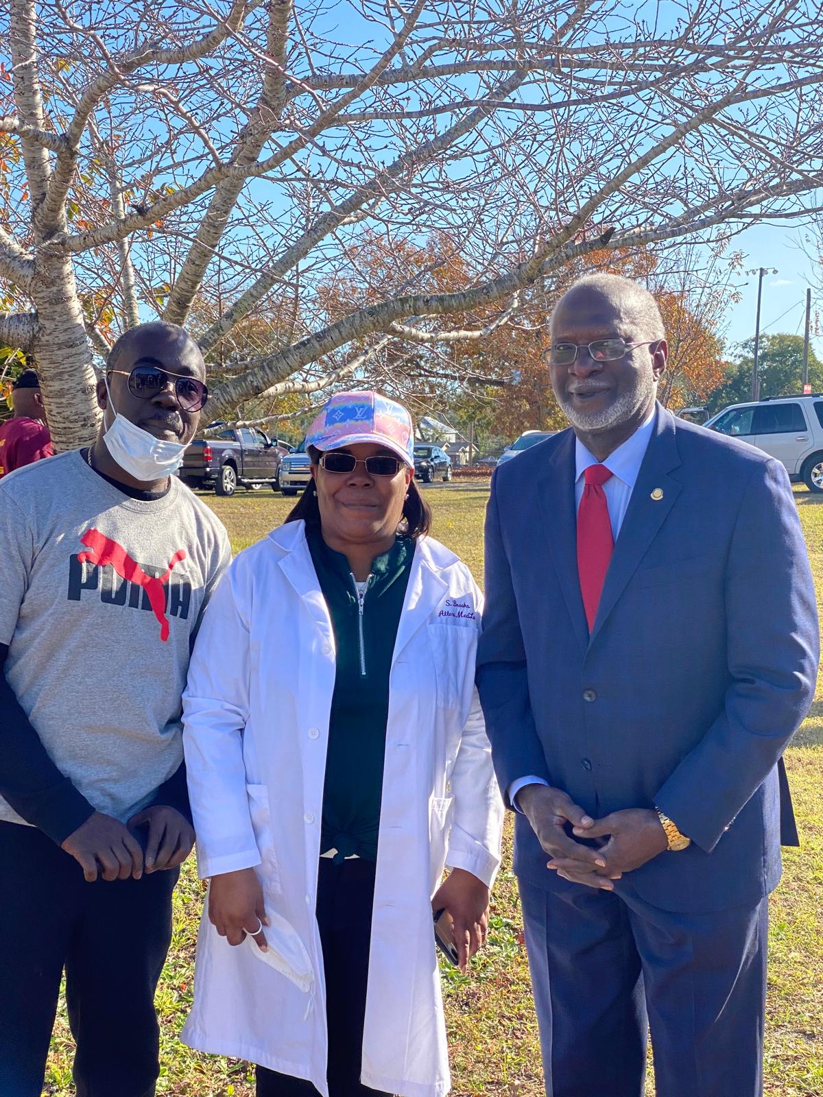 Sandra Brooks in lab coat with community partners and Dr. David Satcher